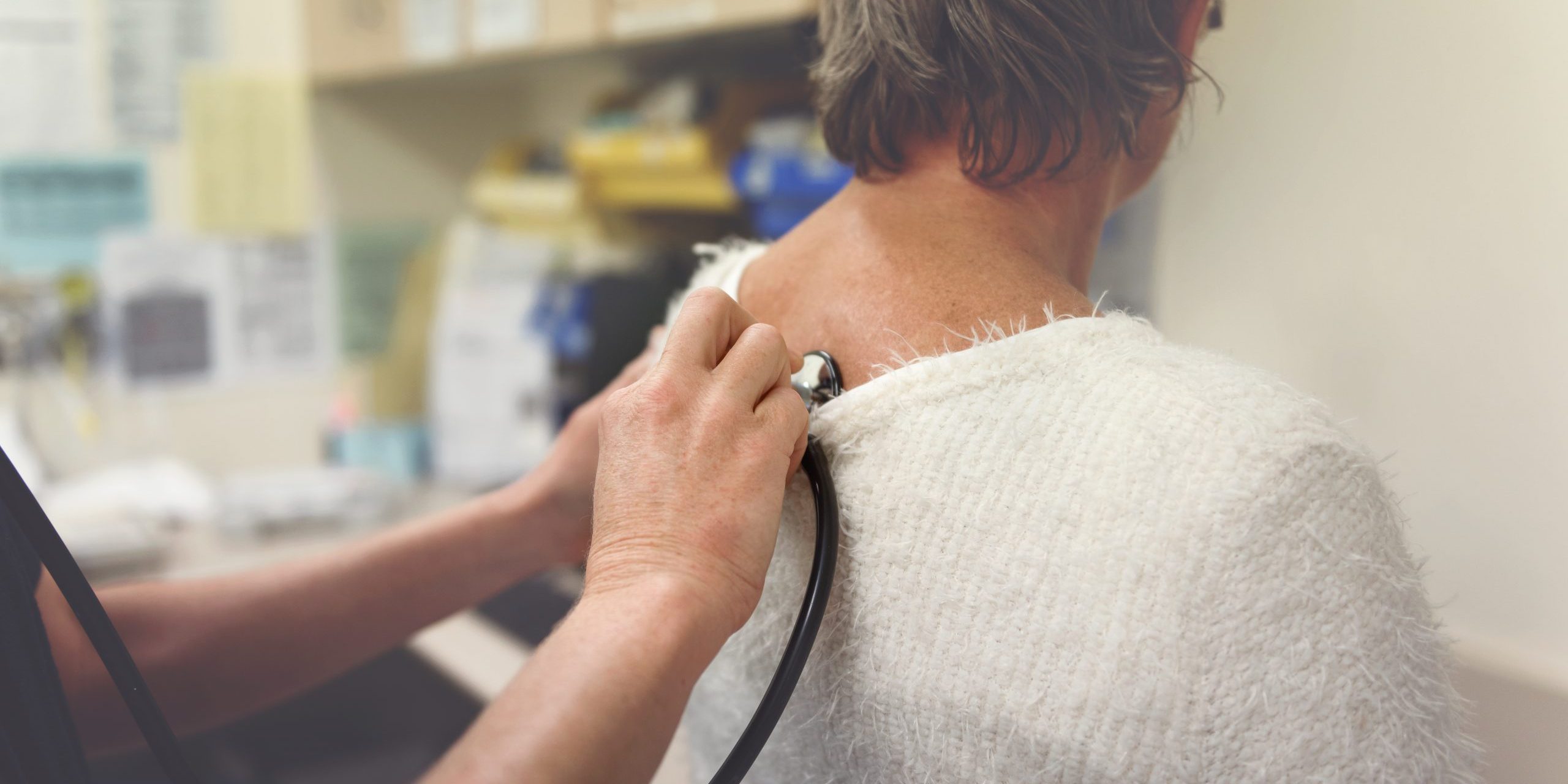 Medical professional using stethoscope on woman's back