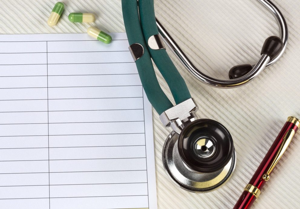 Stethoscope on desk with paper and pen